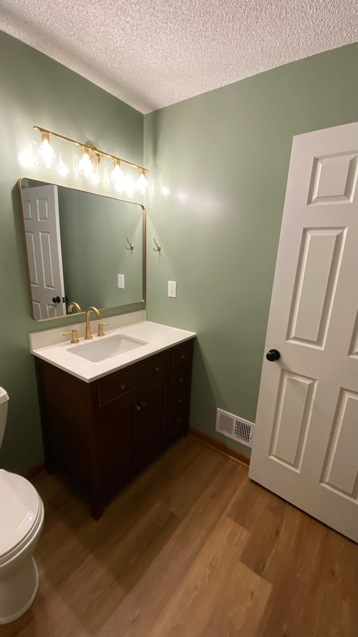 Remodeled bathroom with sage walls and gold fixtures