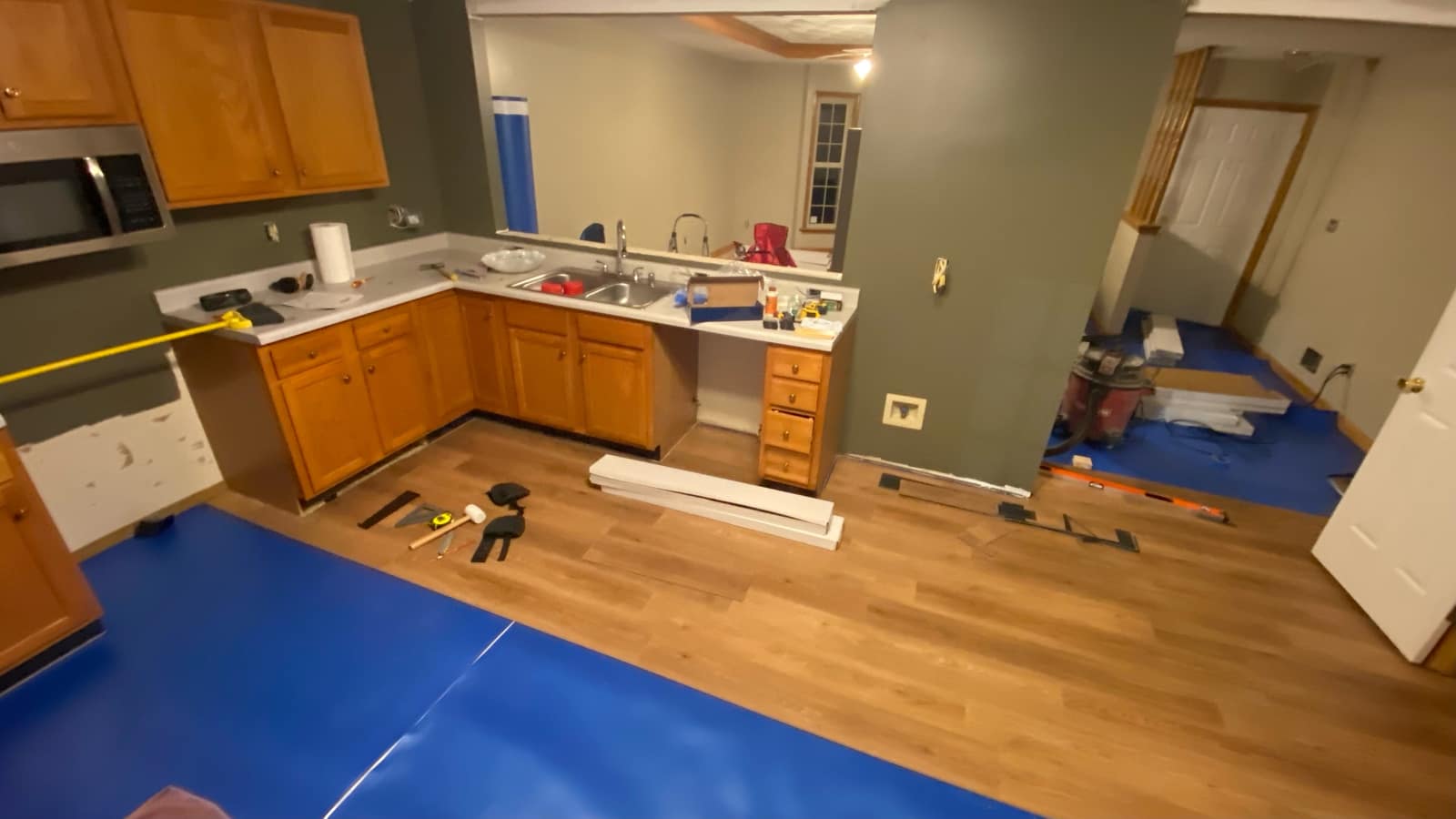 Luxury vinyl plank flooring being installed across the kitchen