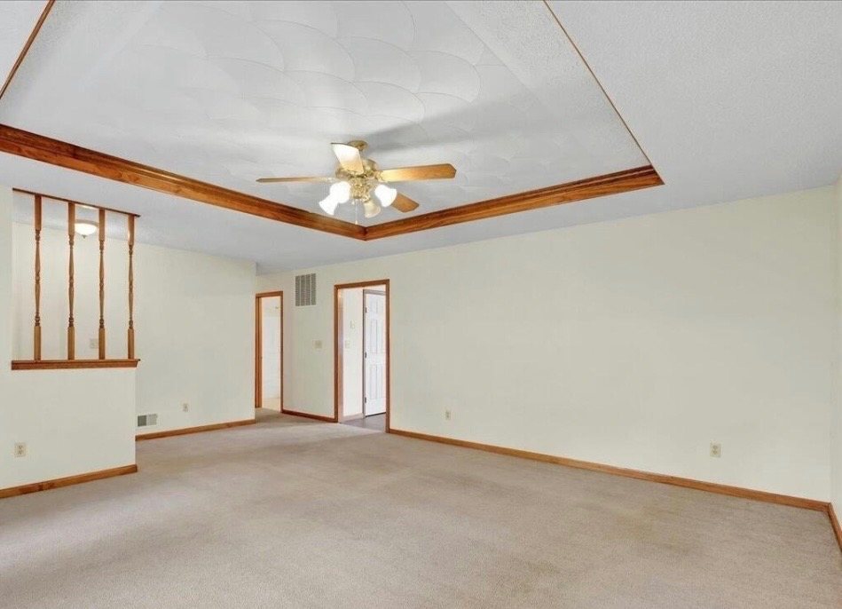 Carpeted living room before renovation, walled off from the kitchen
