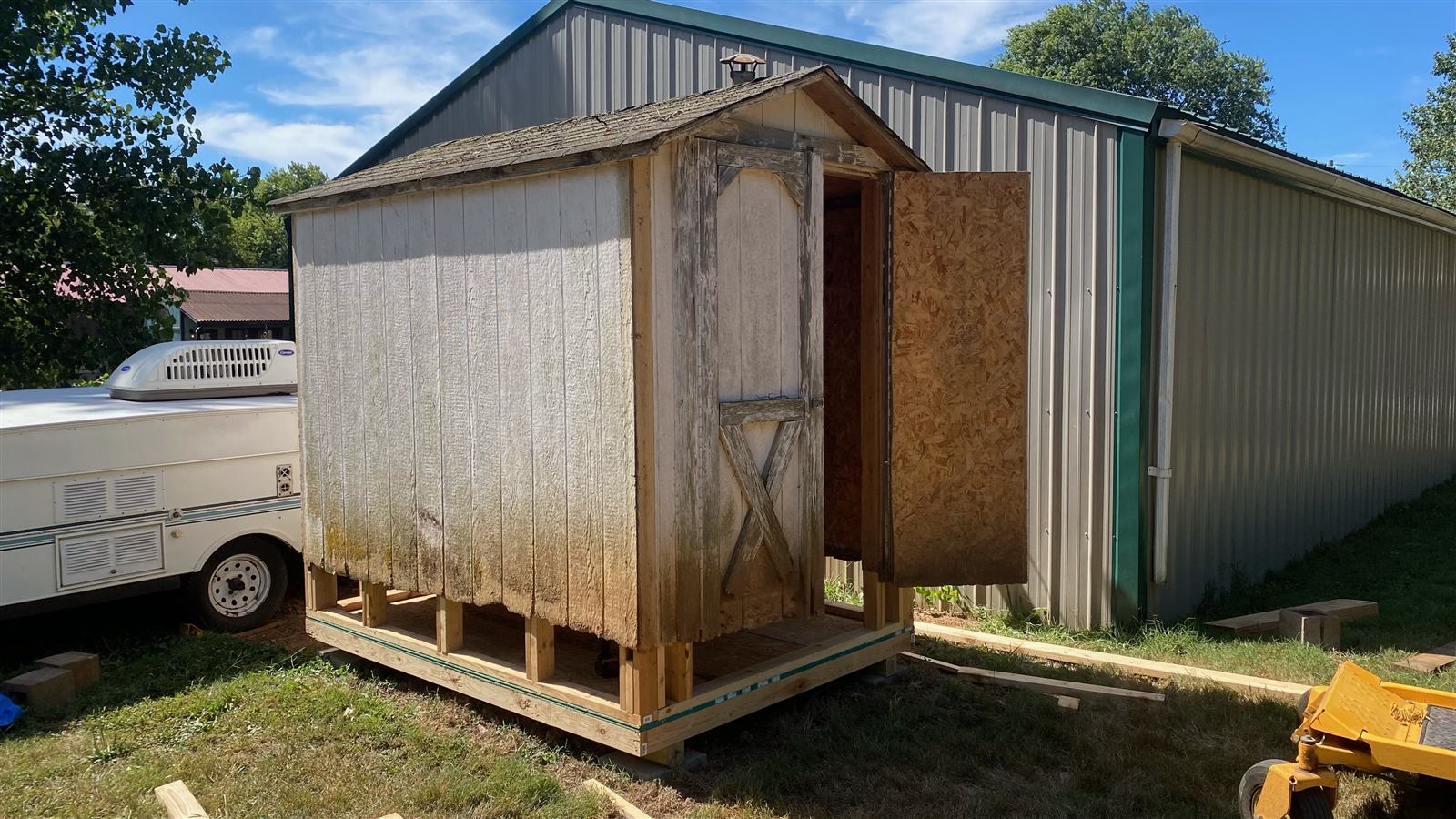 Shed lifted onto a new pressure-treated frame with old siding coming off