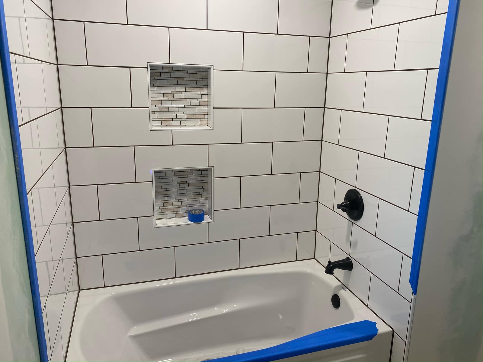 New white tile tub surround with two inlaid mosaic niches